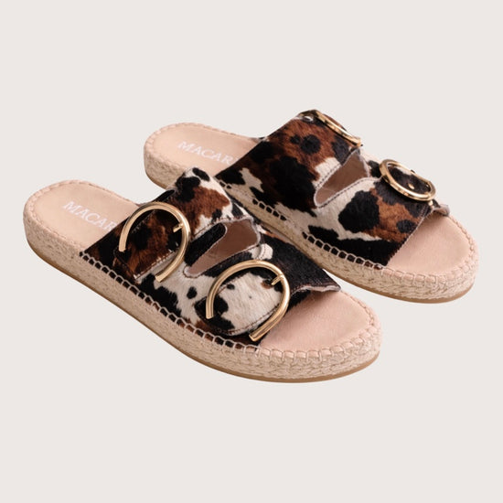 Cow print sandal with gold buckles and a woven sole 