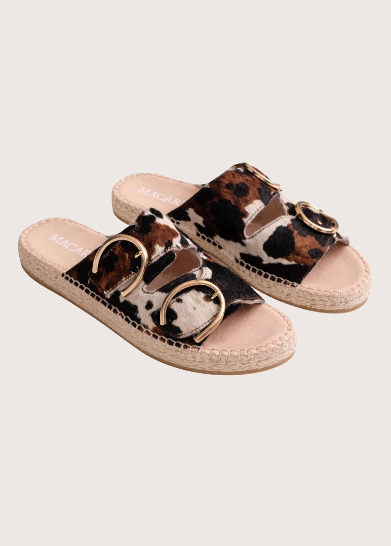 Cow print sandal with gold buckles and a woven sole 