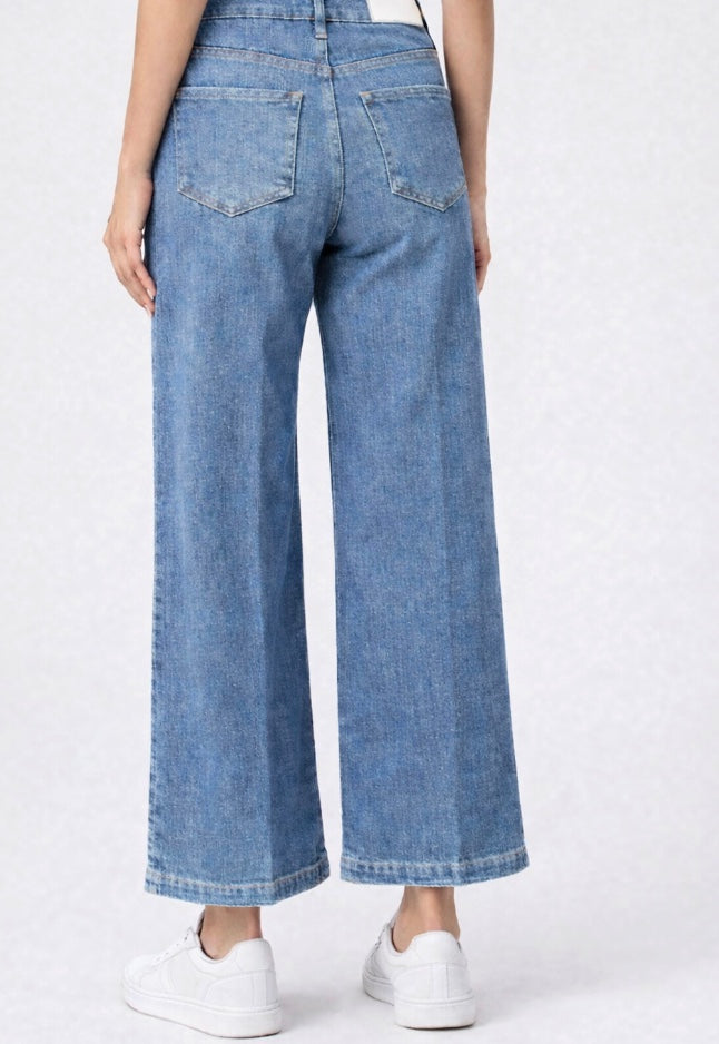 Person wearing light blue wide-leg jeans on a white background