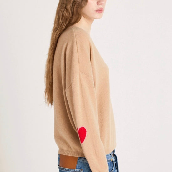 Woman wearing a beige sweater with text and blue jeans on a white background