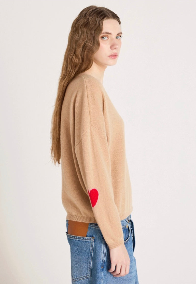 Woman wearing a beige sweater with text and blue jeans on a white background