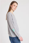 Woman wearing a gray sweater with heart patterns on a plain background