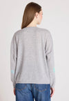 Woman wearing a gray sweater with heart patterns on a plain background