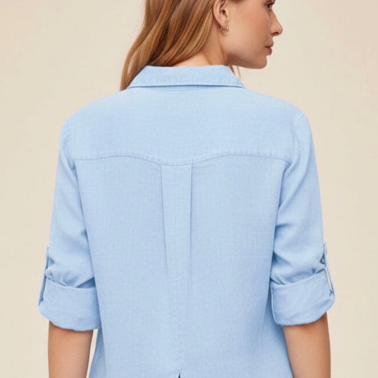 Woman wearing a light blue shirt with rolled-up sleeves on a beige background