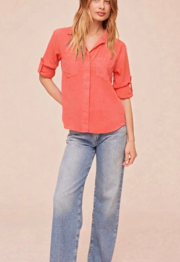 Person wearing a coral shirt with rolled-up sleeves on a beige background