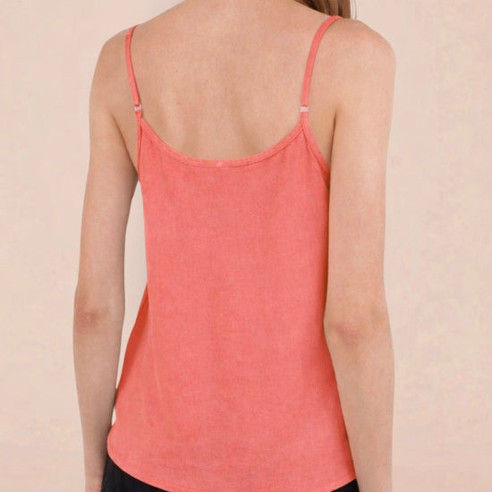 Woman wearing a coral tank top against a plain background