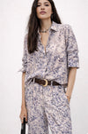 Woman wearing a  blue snake print shirt outfit with a belt on a white background