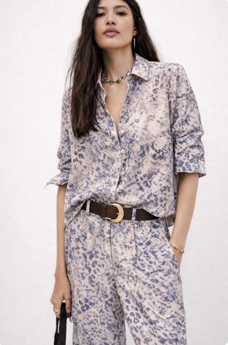 Woman wearing a  blue snake print shirt outfit with a belt on a white background