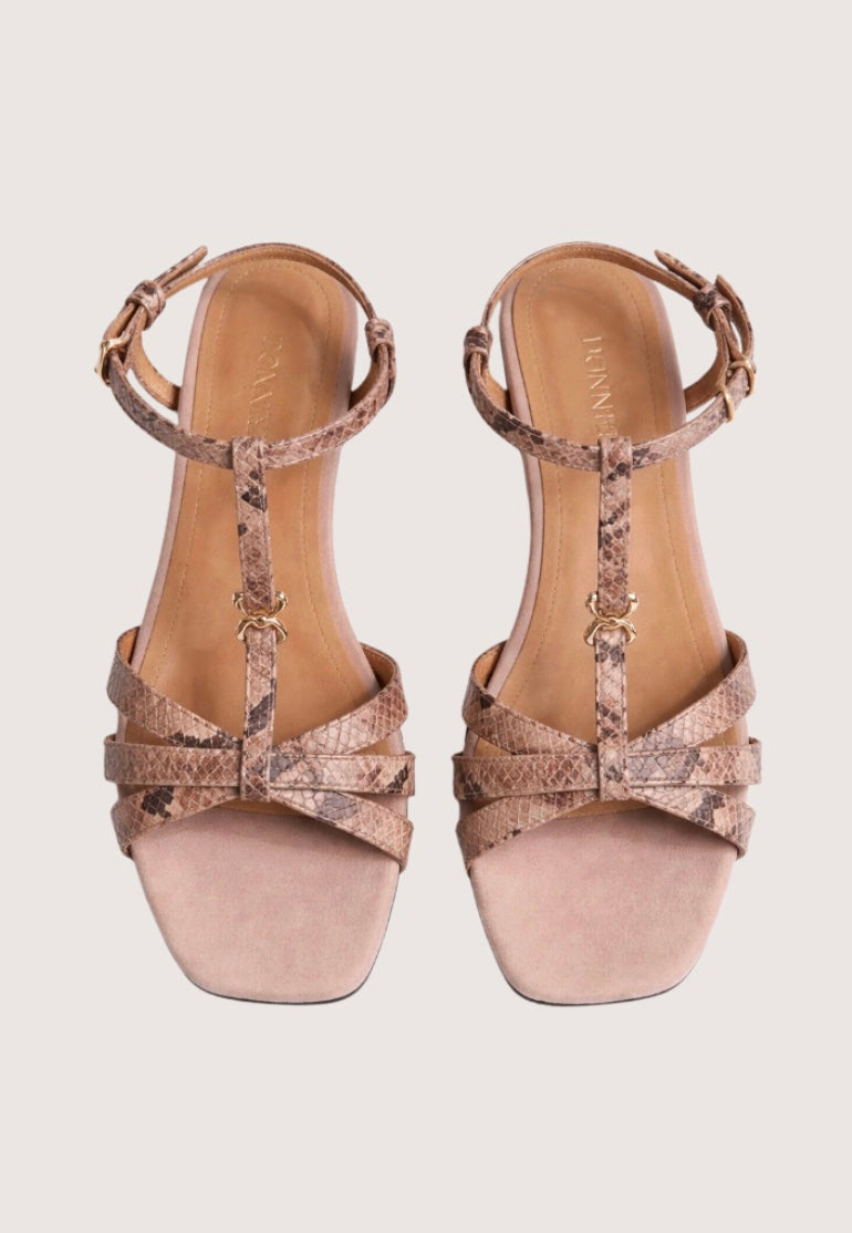 Pair of beige high-heeled sandals with metallic accents on a light gray background