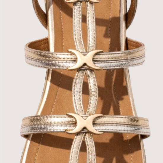 Gold strappy sandal with decorative straps on a neutral background