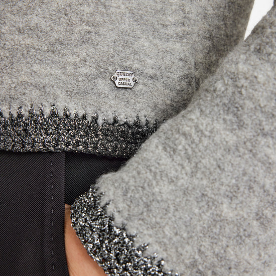 Close-up of a gray textured fabric with a brand logo on a black background