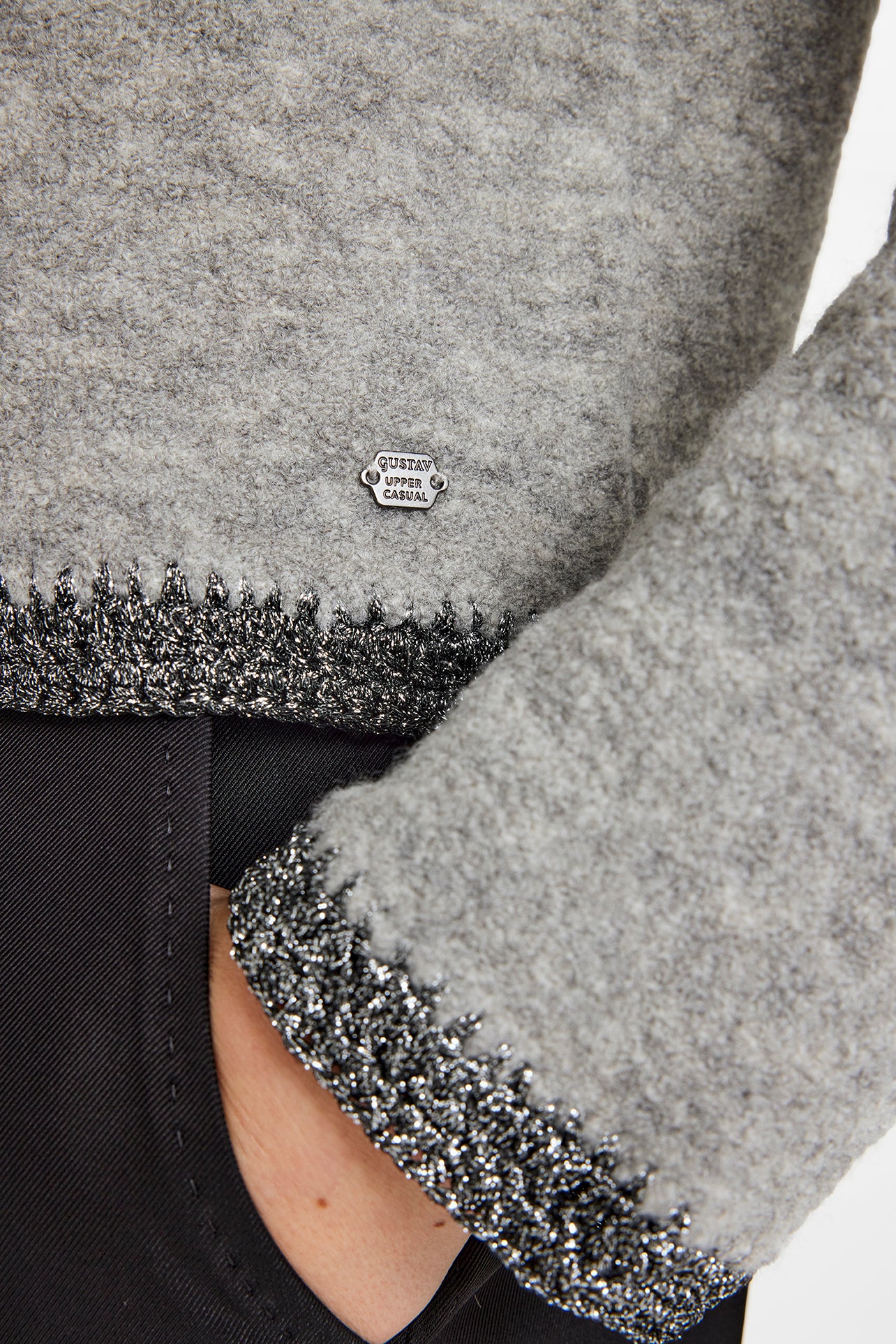 Close-up of a gray textured fabric with a brand logo on a black background