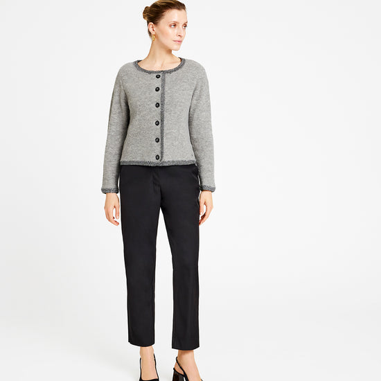 Woman wearing a gray cardigan and black pants on a white background