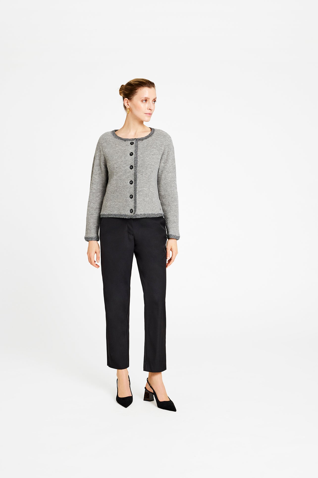 Woman wearing a gray cardigan and black pants on a white background