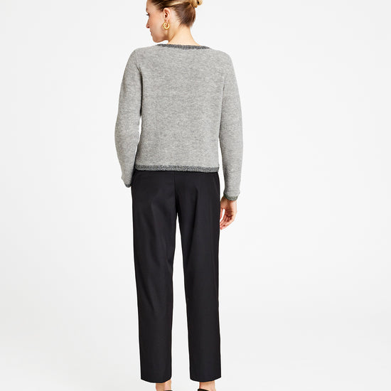 Person wearing a gray sweater and black pants on a white background