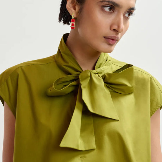 Woman wearing a green blouse with a bow detail on a white background