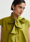 Woman wearing a green blouse with a bow detail on a white background