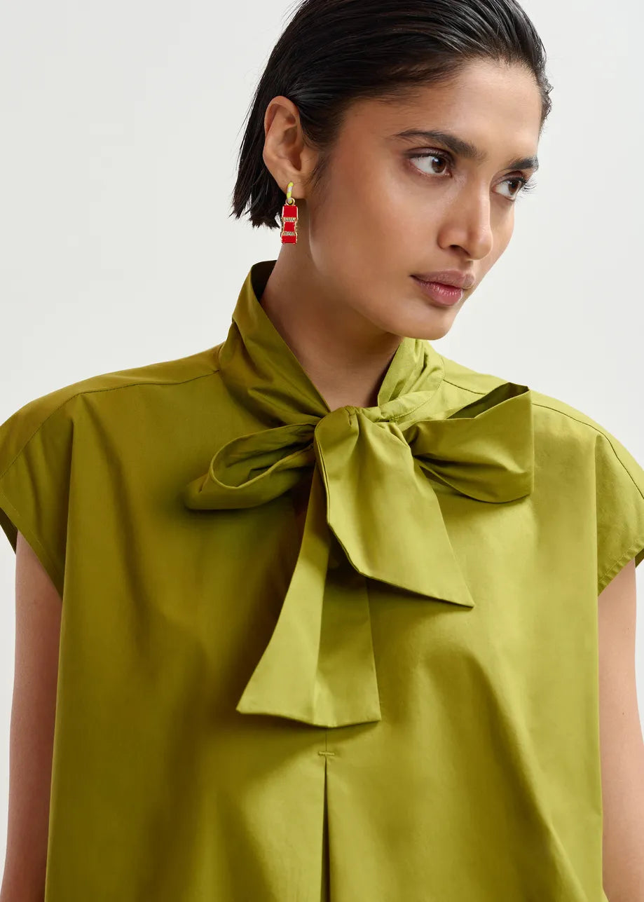 Woman wearing a green blouse with a bow detail on a white background
