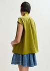 Person wearing a green sleeveless top and denim skirt on a white background