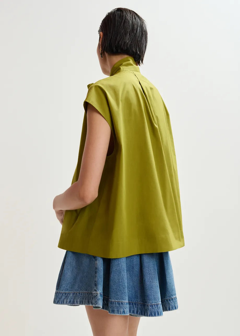 Person wearing a green sleeveless top and denim skirt on a white background