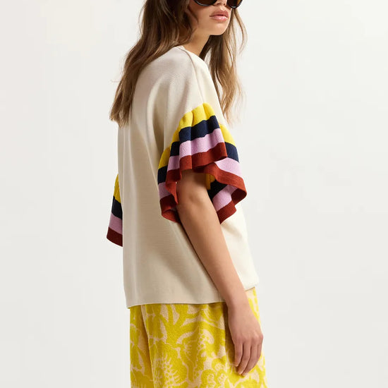 Woman wearing a colorful striped top and yellow skirt on a white background