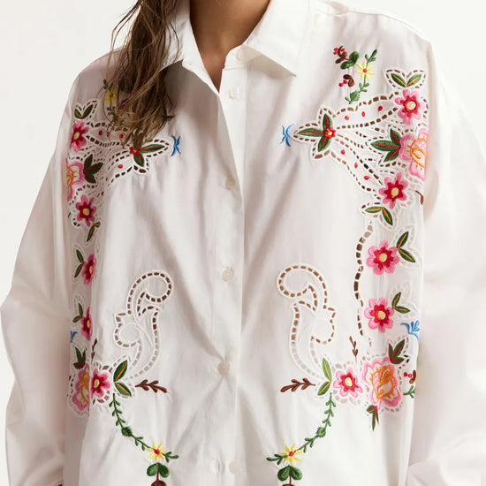 White shirt with colorful floral embroidery on a white background