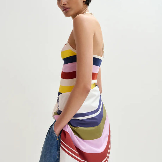 Woman wearing a colorful striped dress with a plain background