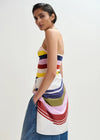 Woman wearing a colorful striped dress with a plain background