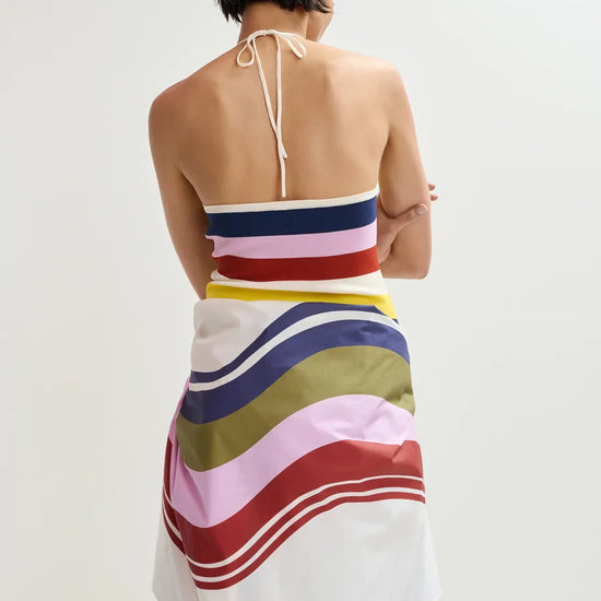 Woman wearing a colorful striped dress with a plain background