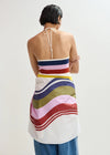 Woman wearing a colorful striped dress with a plain background
