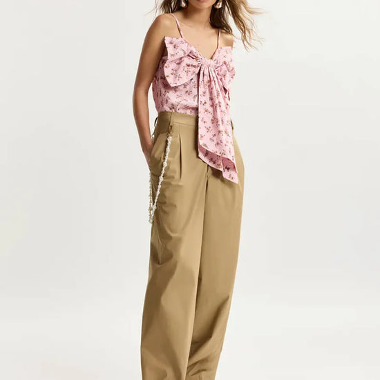Woman wearing a pink floral top and beige pants on a white background