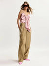 Woman wearing a pink floral top and beige pants on a white background