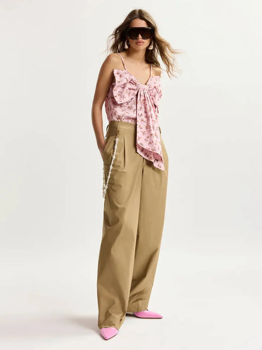 Woman wearing a pink floral top and beige pants on a white background