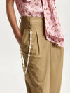 Person wearing beige pants with a pink floral top on a white background
