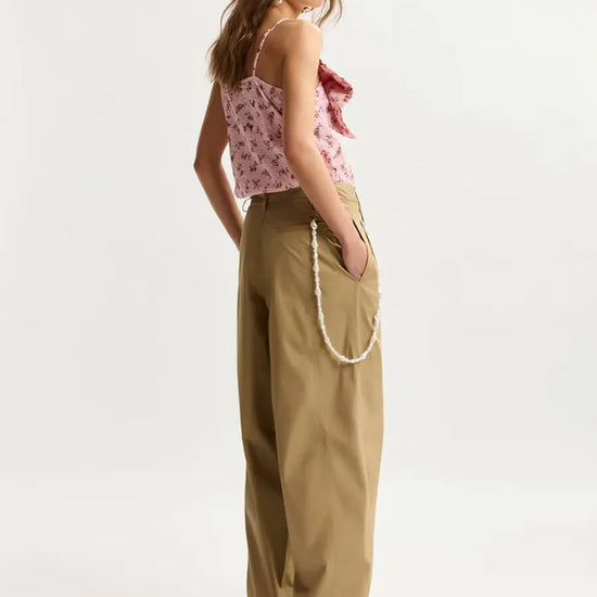 model wearing brown trousers and a pink top facing the right