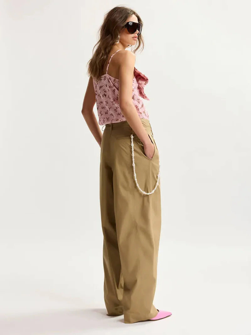 model wearing brown trousers and a pink top facing the right