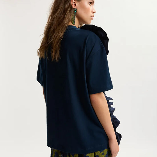 Woman wearing a dark blue top and patterned skirt on a white background
