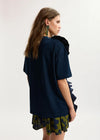 Woman wearing a dark blue top and patterned skirt on a white background