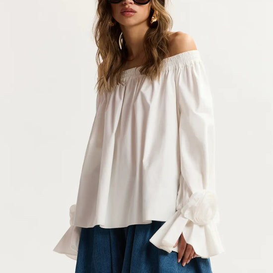 Woman wearing a white off-shoulder top and blue denim skirt on a white background