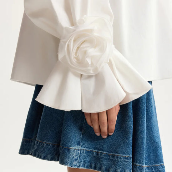 White blouse with ruffled sleeves and a blue denim skirt on a white background