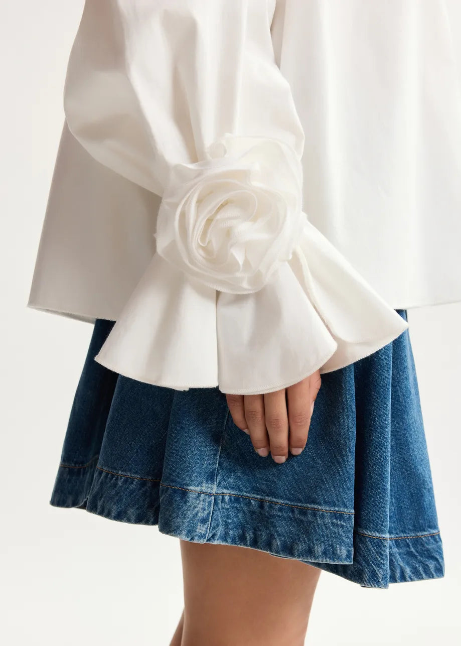 White blouse with ruffled sleeves and a blue denim skirt on a white background