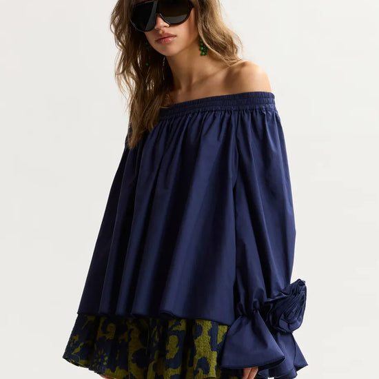 Woman wearing a blue off-shoulder top with a patterned bottom on a white background