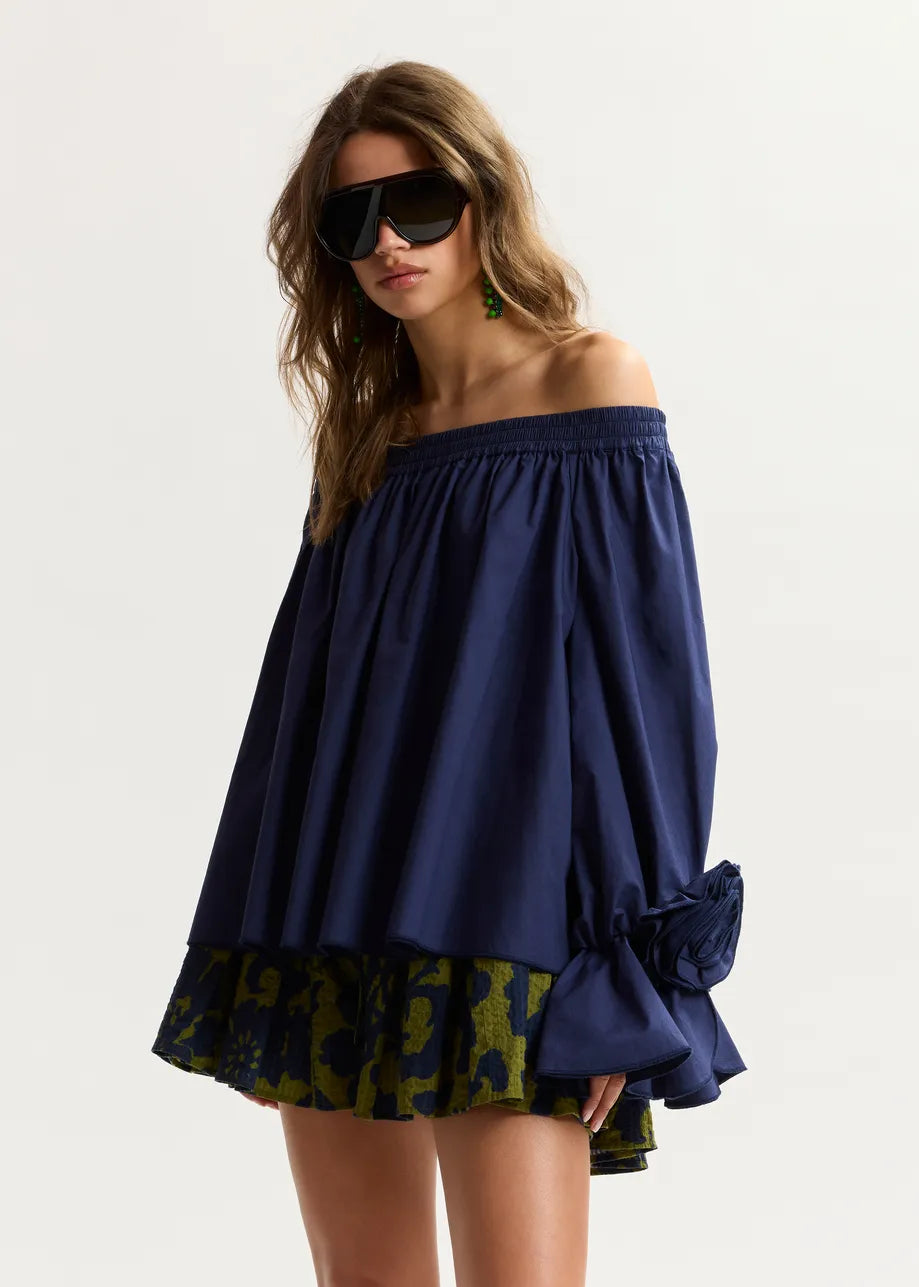 Woman wearing a blue off-shoulder top with a patterned bottom on a white background