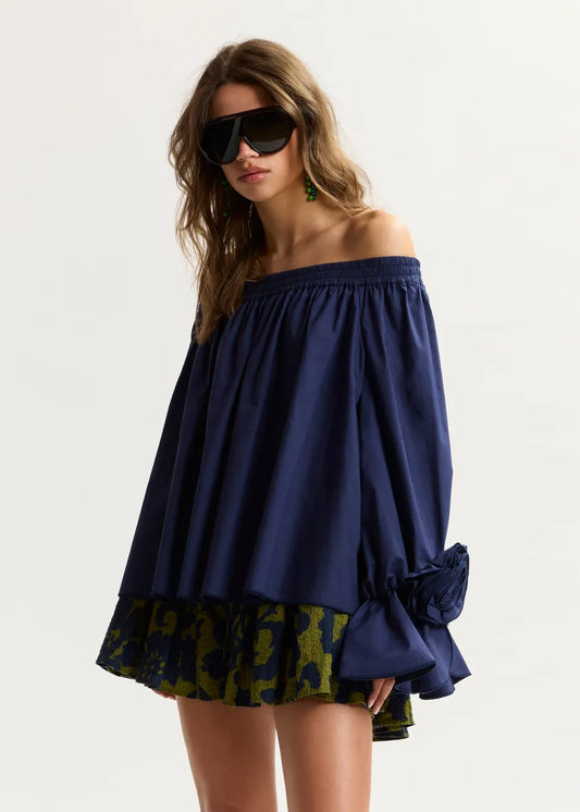 Woman wearing a blue off-shoulder top with a patterned bottom on a white background