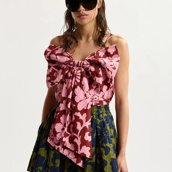 Woman wearing a colorful floral dress with sunglasses on a white background