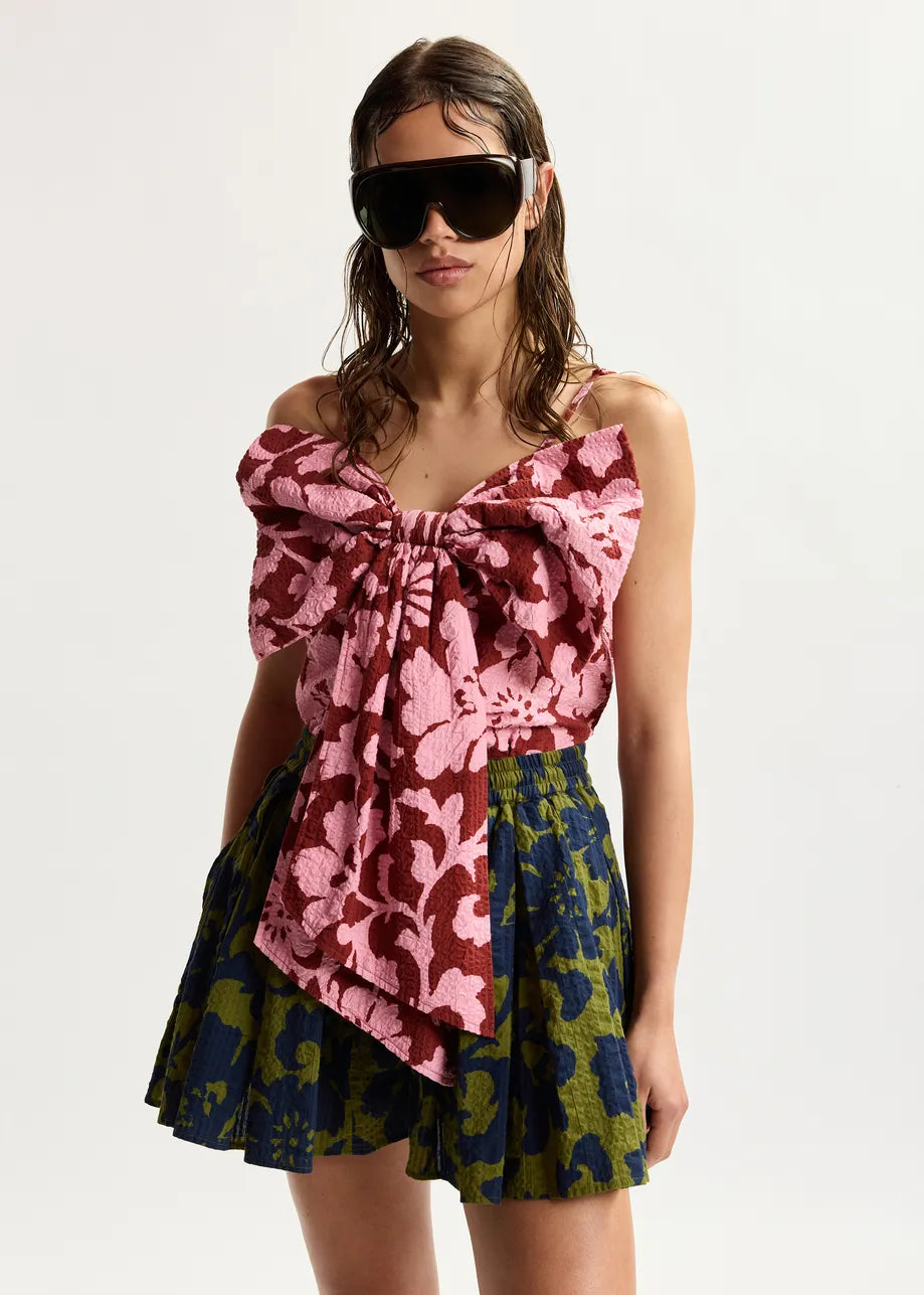 Woman wearing a colorful floral dress with sunglasses on a white background