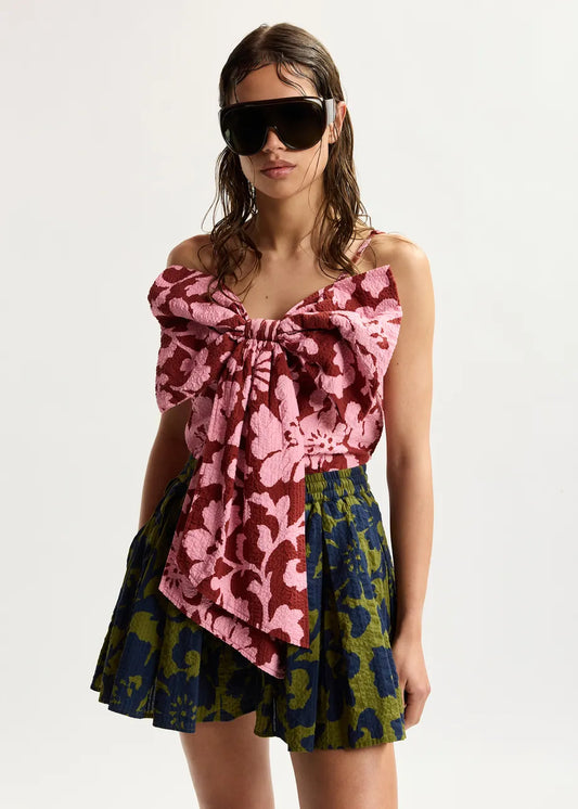 Woman wearing a colorful floral dress with sunglasses on a white background