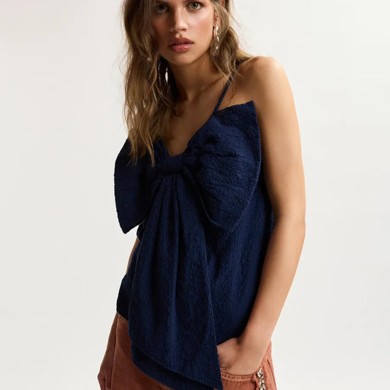 model wearing blue top with a dramatic bow on the front 