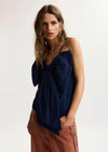 model wearing blue top with a dramatic bow on the front 