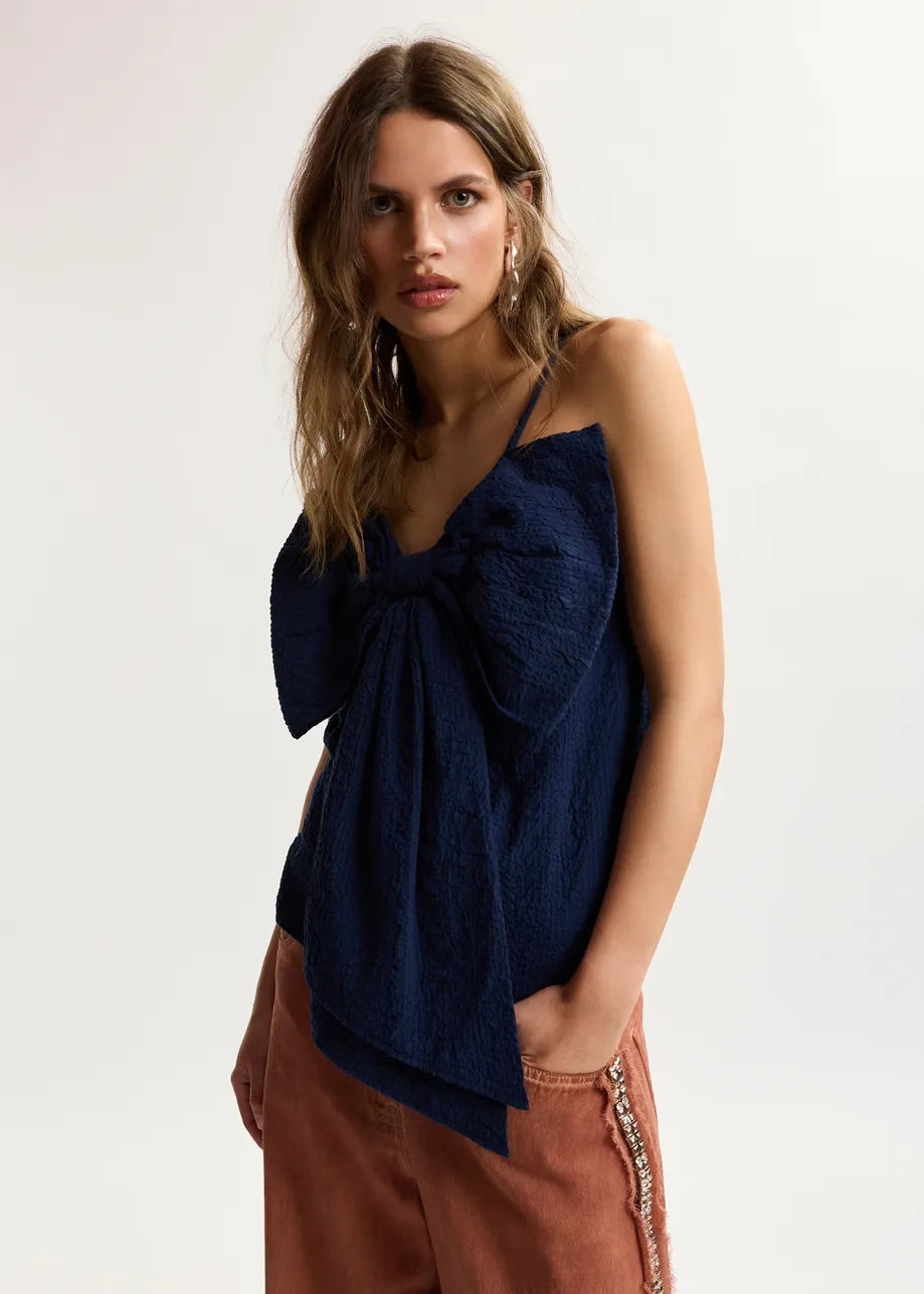 model wearing blue top with a dramatic bow on the front 